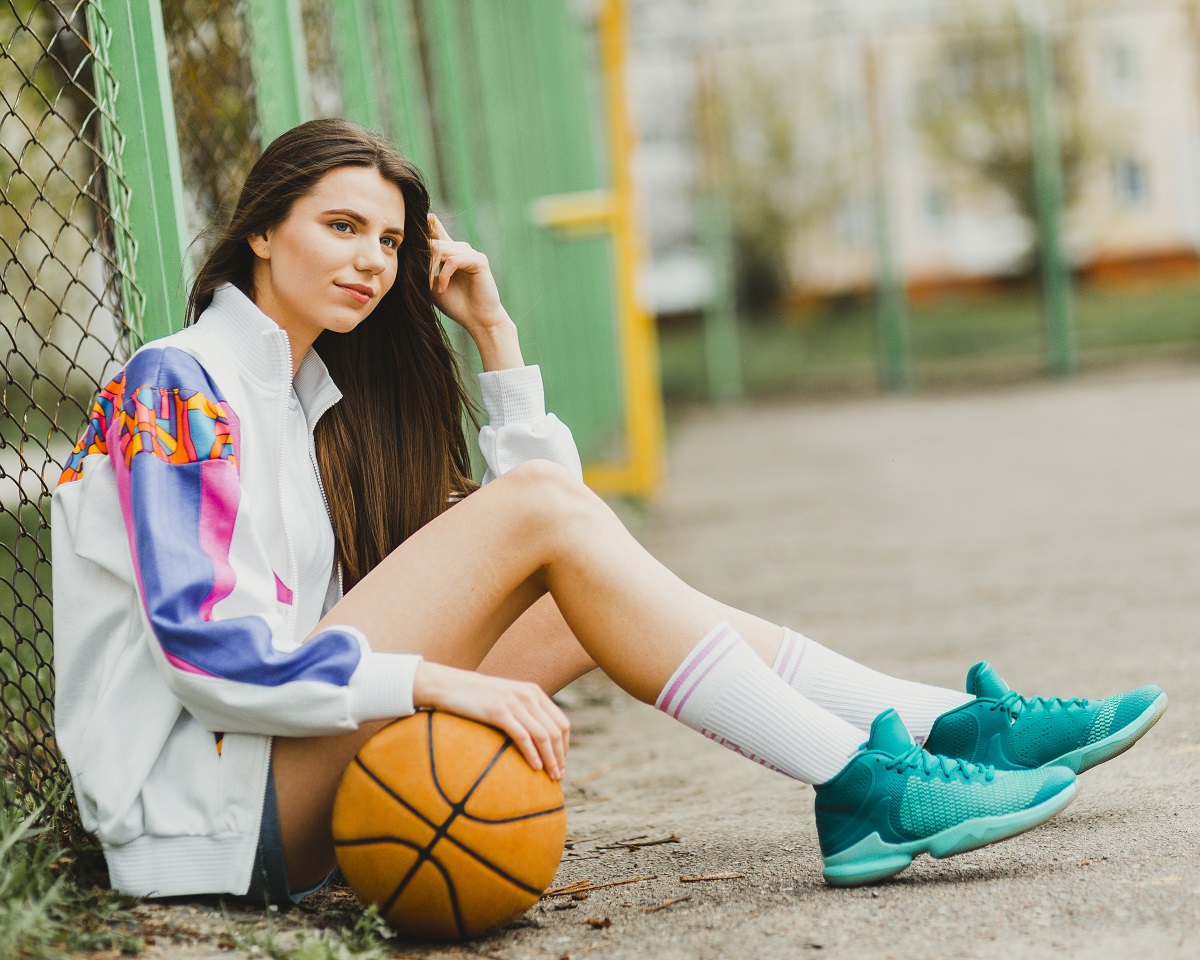 Menina sentada com sua bola de basquete e tênis confortavel
