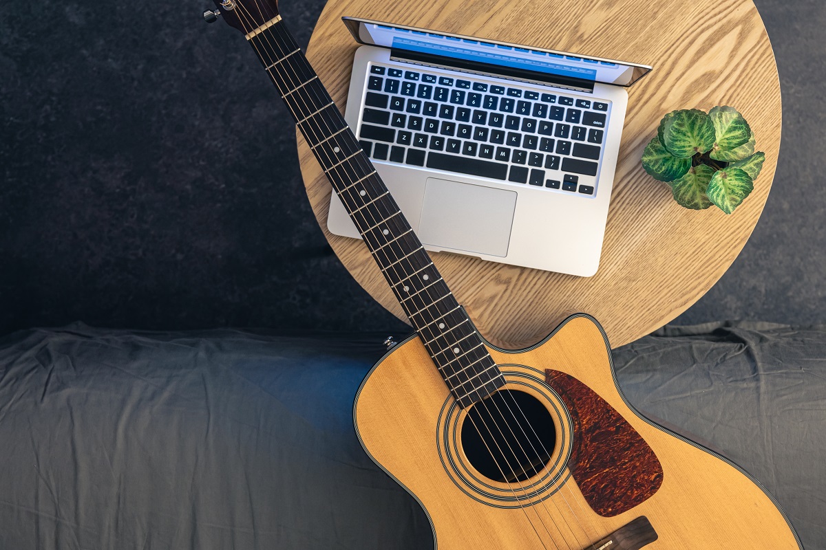 Guitarra acústica e notbook em uma mesa de madeira